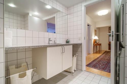 a kitchen with white tiled walls and a sink at Spacious Canal-View Apartment Near Metro in Christianshavn in Copenhagen