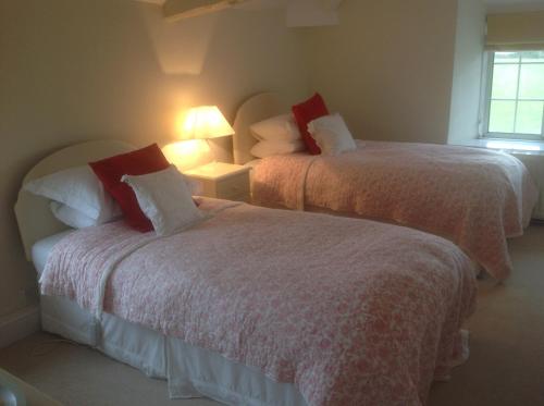 1 dormitorio con 2 camas y almohadas blancas y rojas en The Coach House, en Ross-on-Wye