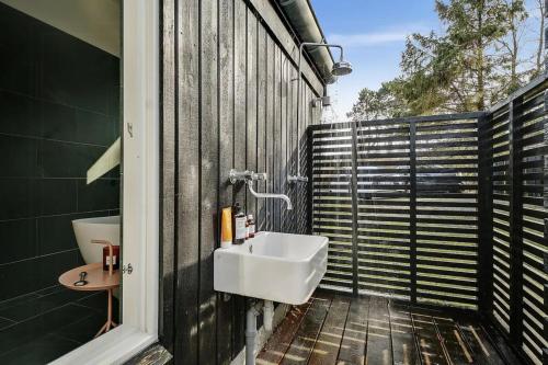 a bathroom with a sink on the side of a fence at Family House In Two Homes At Fyns Head in Martofte