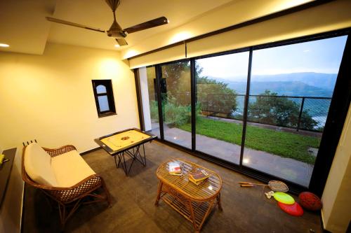 a living room with a large window with a table and chairs at Par-X - Villa Sukoon - 3BHK Valley View - Leave the World Far Behind in Satara