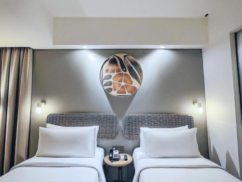 two beds in a hotel room with white pillows at Neo Hotel Puri Indah in Jakarta