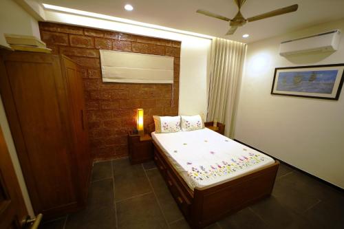 a small bedroom with a bed and a brick wall at Par-X - Villa Sukoon - 3BHK Valley View - Leave the World Far Behind in Satara