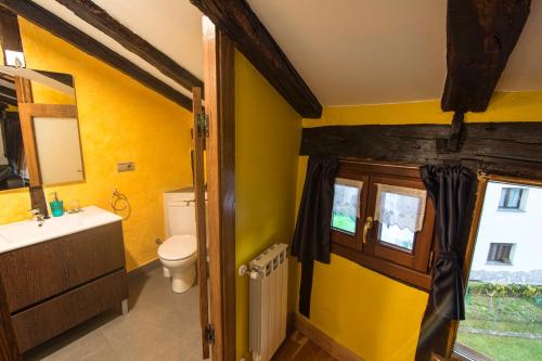 a bathroom with yellow walls and a toilet and a window at Zumargain in Asteasu