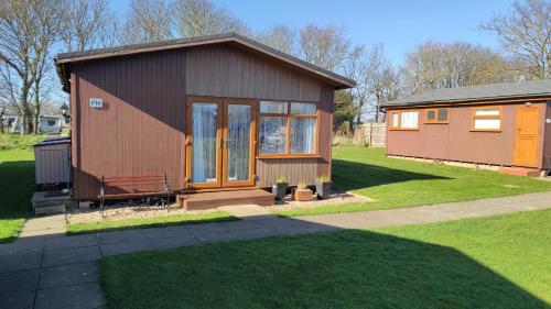a small house in a yard with a green lawn at Quiet 6 berth pet friendly chalet near beach in Mablethorpe