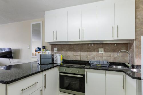 a kitchen with white cabinets and a sink at Mzingazi Waterfront Accommodation, On The Bay Waterfront Villa's in Richards Bay