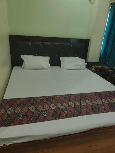 a bed with a black headboard and two pillows at HOTEL AV Priya Rajgir in Rājgīr