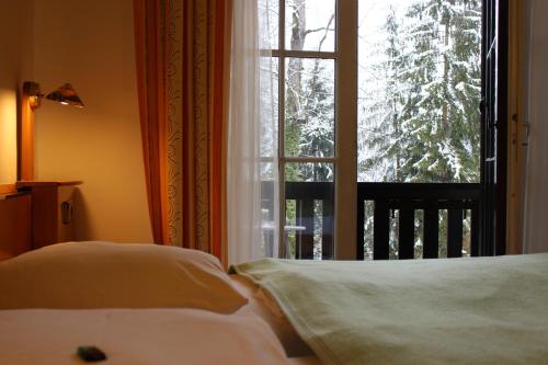 a bedroom with two beds and a window with a view at Hotel Restaurant Schweizerhaus in Klagenfurt