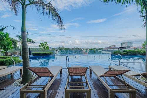 a swimming pool with three chairs and palm trees at Luxury Corner Suite 1 Bedroom plus Den Top Floor Birds Eye View Spacious 668 square Feet in Iloilo City