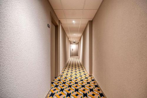 a long hallway with a floor of black and yellow tiles at ALMA Grand Place Hotel in Brussels