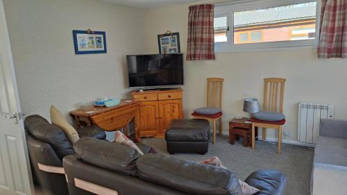 a person sitting on a couch in a living room at Quiet 6 berth pet friendly chalet near beach in Mablethorpe