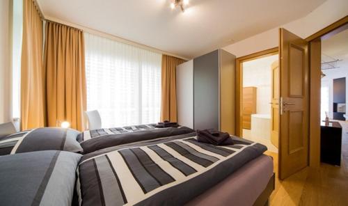 Dos camas en una habitación con una gran ventana. en Residenz Ambassador B23, en Leukerbad