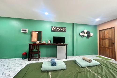 a green room with a bed and a desk at Koon Hom Apartment in Ban Dung