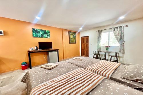 a bedroom with two beds and a desk and a television at Koon Hom Apartment in Ban Dung