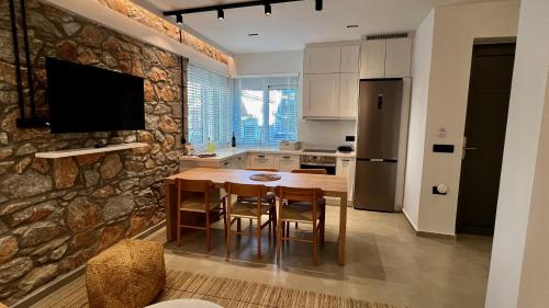 a kitchen with a wooden table and a stone wall at Aeolian apartment in Mytilini