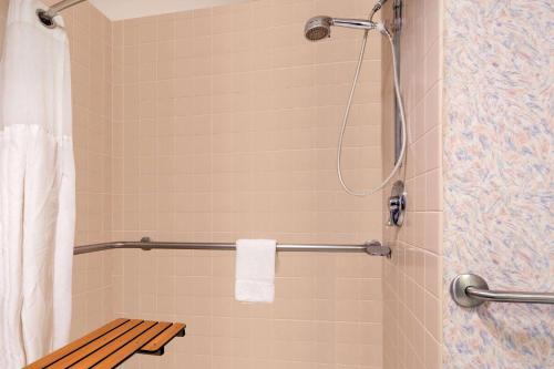 a shower with a bench in a bathroom at Ramada by Wyndham Kent Seattle Area in Kent