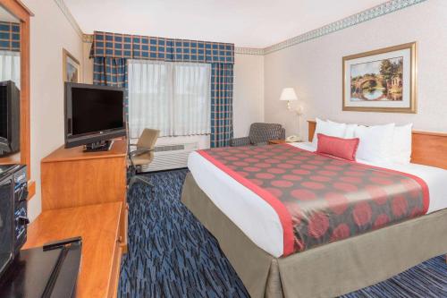 a hotel room with a bed and a flat screen tv at Ramada by Wyndham Kent Seattle Area in Kent