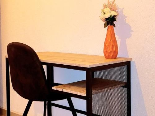 une table avec un vase de fleurs et une chaise dans l'établissement Le Marceau Cour Extérieure, à Narbonne