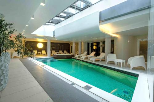 a swimming pool in a house with white chairs at Wellton Centrum Hotel & SPA in Rīga