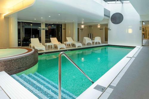 a swimming pool in a hotel with chairs and tables at Wellton Centrum Hotel & SPA in Rīga