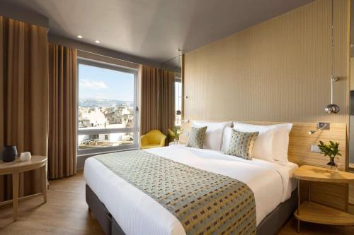 a bedroom with a large bed and a large window at Wyndham Grand Athens in Athens