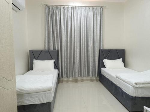 two beds in a room with a window at Studio 1 Bedroom 2 twin beds in Al Ain