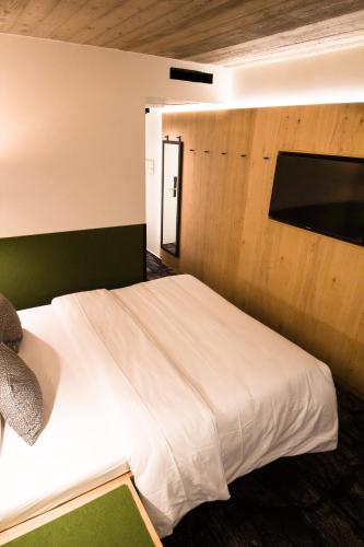 a bedroom with a white bed with a wooden wall at De Brauhotel - Hôtel de la Brasserie Nationale in Bascharage