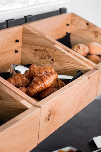 a wooden box filled with different types of bread at De Brauhotel - Hôtel de la Brasserie Nationale in Bascharage