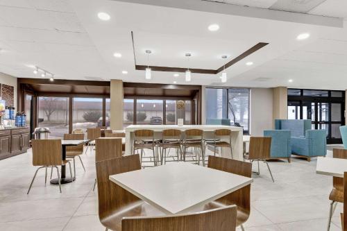 a dining room with tables and chairs and windows at Clarion Pointe Near Erie Casino in Erie
