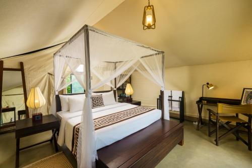 a bedroom with a canopy bed and a desk at Makini Bush Camp, Yala in Yala