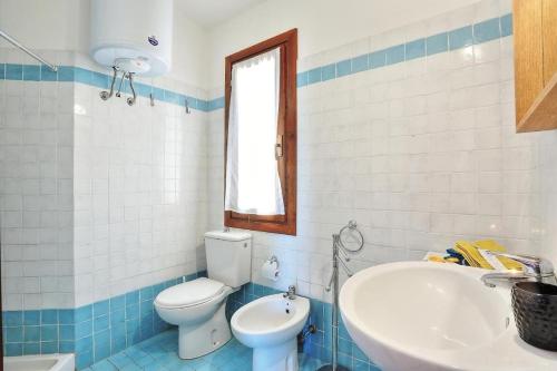 Un baño azul y blanco con inodoro y lavabo. en Deluxe Villa Sardinia Holidays, en Costa Paradiso