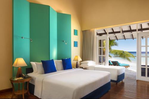 a bedroom with two beds and a view of the beach at Adaaran Select Meedhupparu - with Dine around Premium All inclusive - 24 hours in Meedhoo