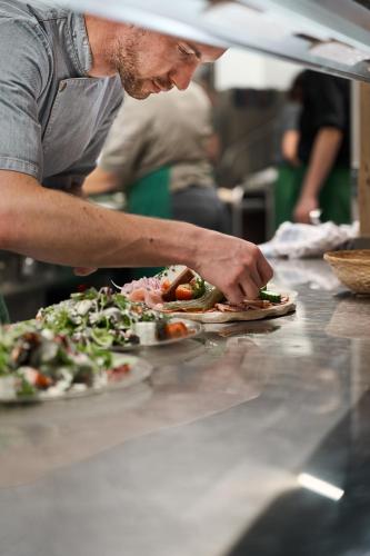 a man making pizzas on a counter in a kitchen at Baumhotel in Kopfing im Innkreis