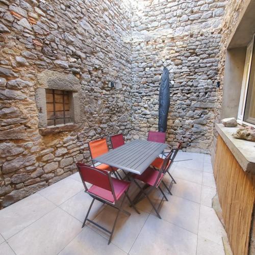 une table et des chaises sur une terrasse avec un mur en pierre dans l'établissement Le chant des vignes - Maison pour 6 avec patio, à Aigne