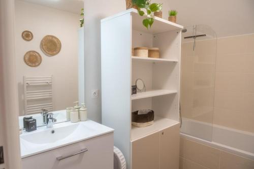 une salle de bain blanche avec un lavabo et une douche dans l'établissement Marcq en Baie, appartement neuf, à Saint-Valery-sur-Somme