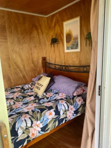 a bedroom with a bed with a floral comforter at Waitomo Farmstay - Cabin 3 and 4 in Waitomo Caves