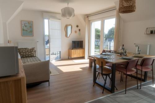 un salon avec une table, des chaises et une télévision dans l'établissement Marcq en Baie, appartement neuf, à Saint-Valery-sur-Somme
