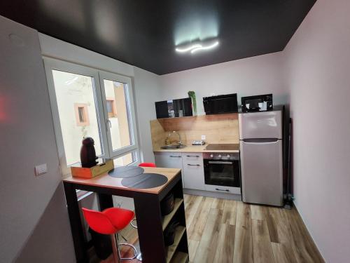 - une cuisine avec un comptoir, un réfrigérateur et une table dans l'établissement Cerises Love- Love room- Balnéo, à Sarralbe