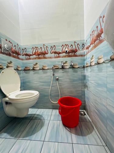 a bathroom with a toilet and a red bucket at Vaisharad Homestay Near Kovalam Beach in Trivandrum