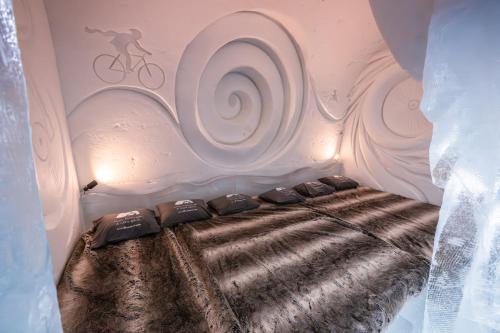 a room with a bed with a painting on the wall at Arctic SnowHotel & Glass Igloos in Sinettä