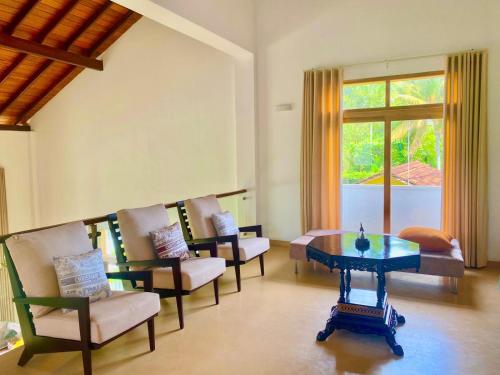 a living room with chairs and a table and a window at Star Light Tropical Villa in Bentota