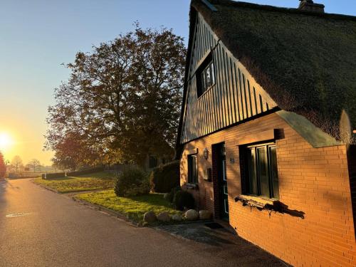 an old brick house on a street with the sunset at Reetdachkate am Deich in Seester