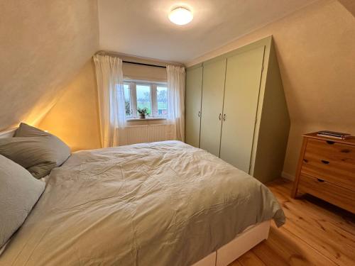 a bedroom with a bed and a dresser and a window at Reetdachkate am Deich in Seester