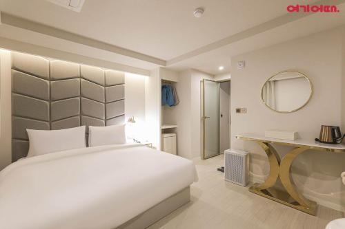 a bedroom with a large white bed and a mirror at Deokcheon Den Basta Hotel in Busan