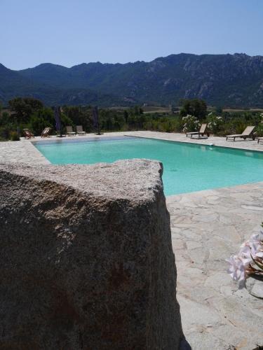 une piscine d'eau bleue et des montagnes en arrière-plan dans l'établissement Le chai, belle villa pour 13 personnes au coeur d'un vignoble avec piscine, à Sartène