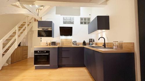 une cuisine avec des armoires noires et un escalier dans l'établissement Coup de Coeur Angevin - Hypercentre - Calme - Cozy, à Angers
