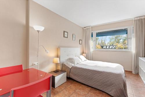 ein Schlafzimmer mit einem Bett, einem Schreibtisch und einem Fenster in der Unterkunft Acogedor estudio en Pedregalejo junto al mar in Málaga