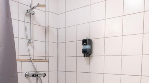 a white tiled shower with a black phone on the wall at Hotel Assens in Assens