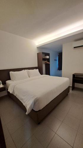a bedroom with a large bed with white sheets at Hotel Al Abraar in Melaka