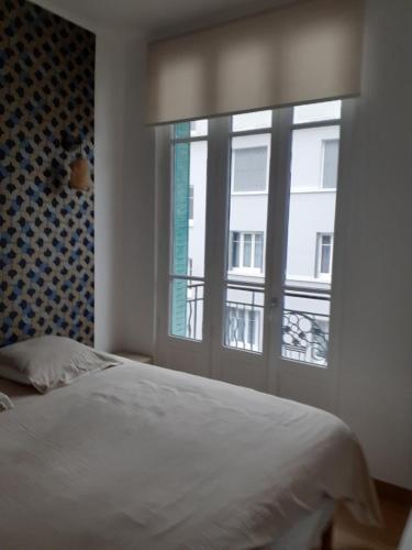 une chambre avec un lit et une grande fenêtre dans l'établissement Charmant appartement quartier des thermes, à Vichy