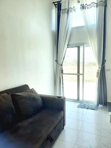a living room with a couch and a large window at VicaWorld in Prathai